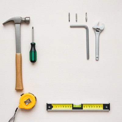 Detailed flat lay of essential tools for flat pack furniture assembly including a Phillips head screwdriver, hammer, Allen wrench, level, and measuring tape on a clean wooden background