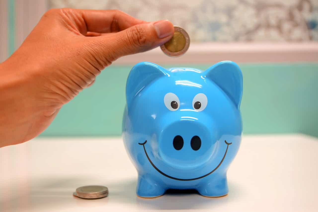 blue piggy bank with a hand adding a coin to it